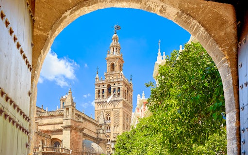 Seville's Giralda tower framed by an archway with clear blue sky.