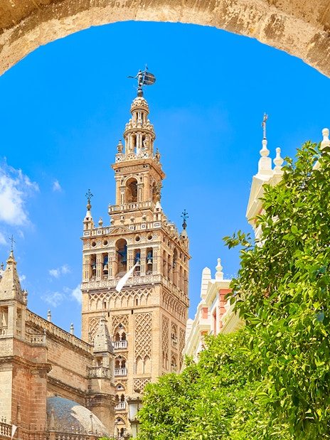 Seville's Giralda tower framed by an archway with clear blue sky.