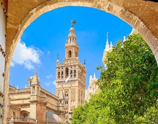 Seville's Giralda Tower framed by an archway with clear blue sky.