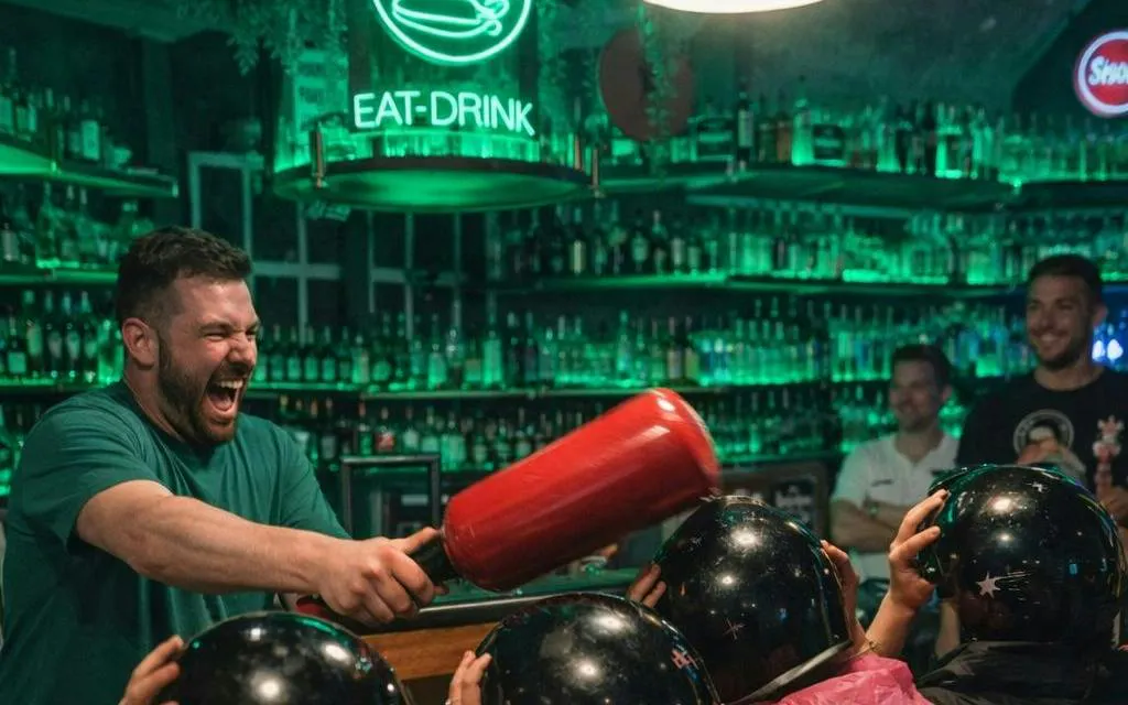 Man enjoying a lively game with friends at a Prague bar during a self-guided pub crawl.