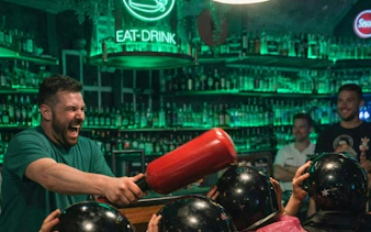 Man enjoying a lively game with friends at a Prague bar during a self-guided pub crawl.
