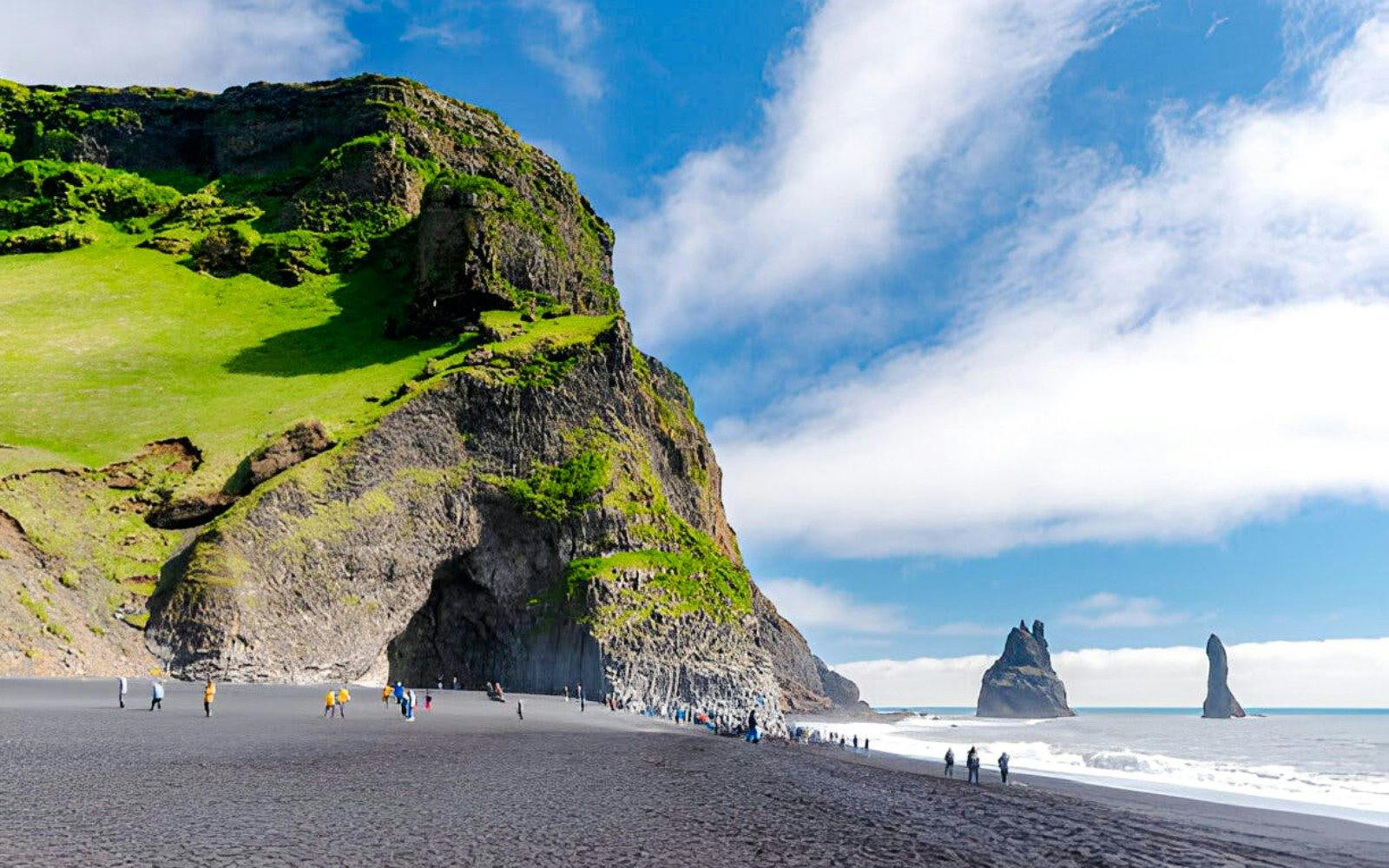 Reynisfjara black sand beach with basalt columns and sea stacks in Iceland.