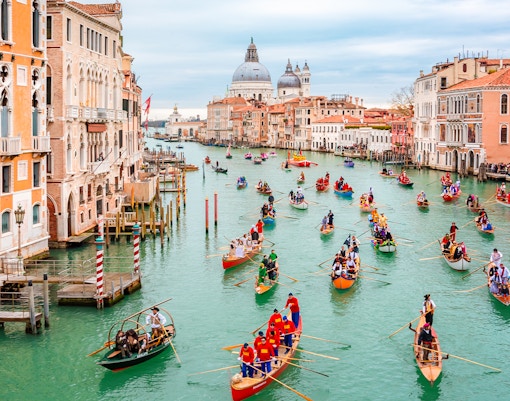 Gondola boats in water parade during Venice carnival opening.