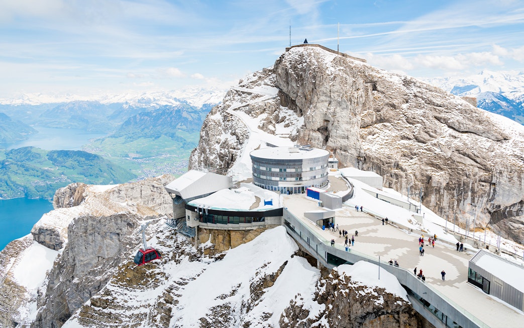 Mount Pilatus summit with visitors and cable car, overlooking Lake Lucerne, Switzerland.