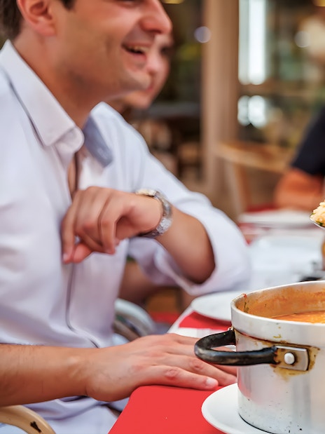Tourist enjoying traditional dish with guide at Lisbon restaurant during Baixa food walk.