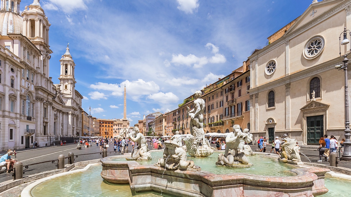 Tourists walking by the Fountain of Neptune in Piazza Navona, Rome.