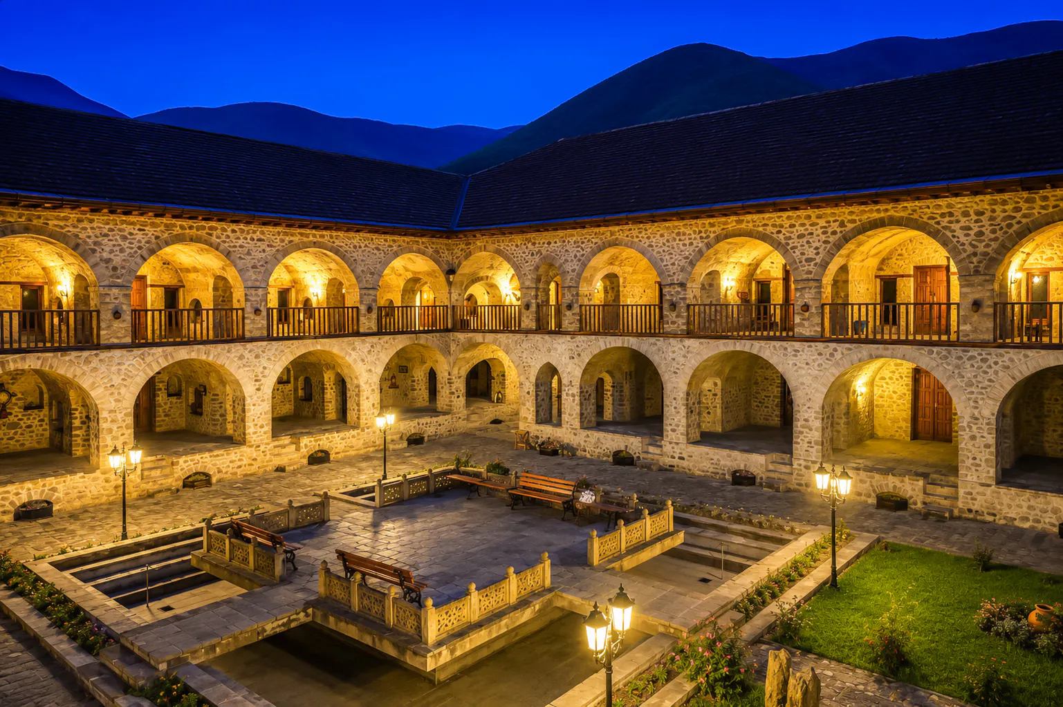 Courtyard of historic Sheki Caravanserai lit at night, featuring stone arches and benches, Sheki, Azerbaijan.