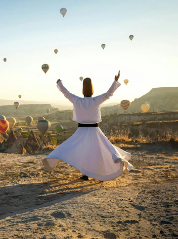 Whirling dervish performing in Cappadocia with hot air balloons in the background.