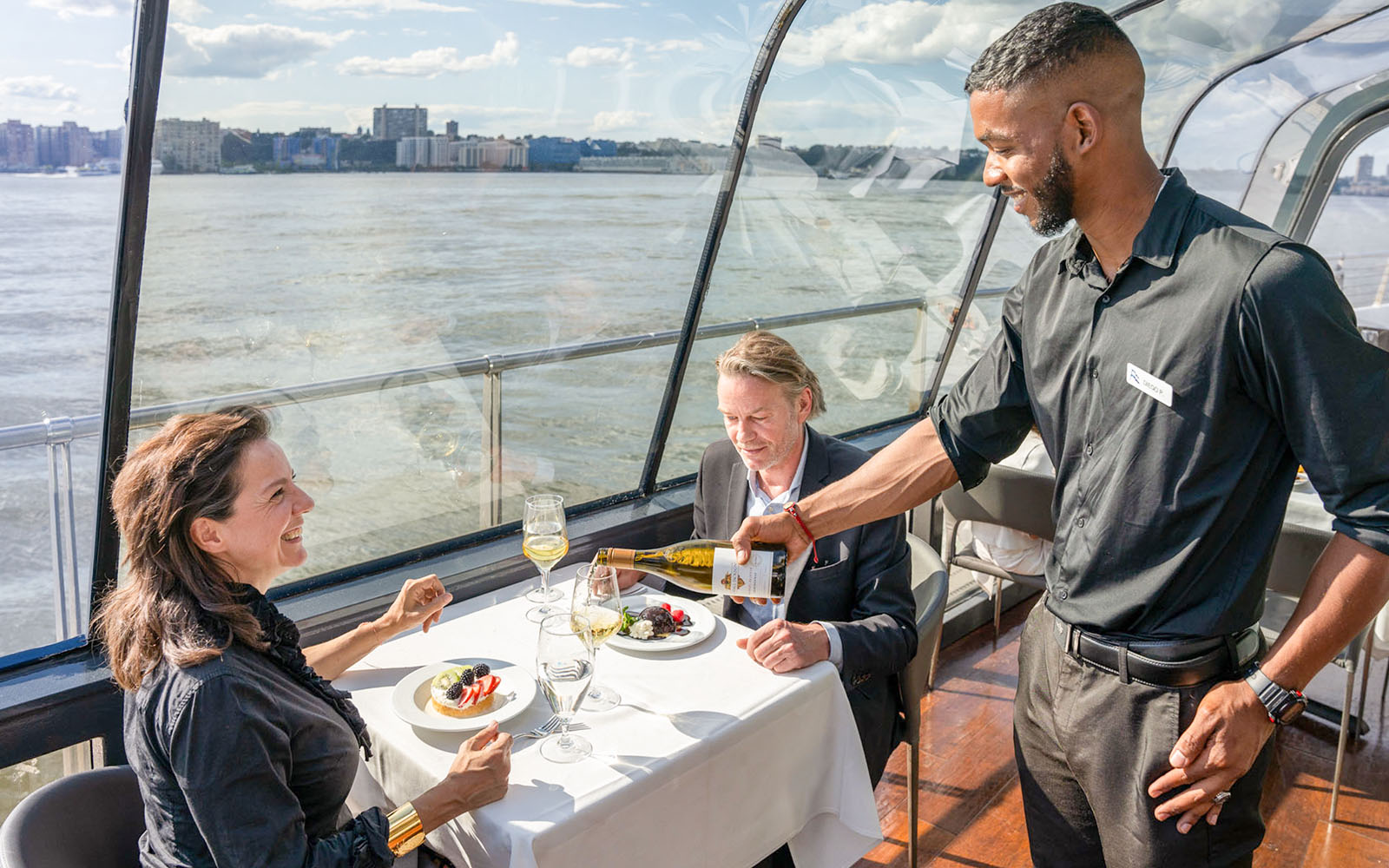 Server pouring wine during lunch on a cruise with river view.