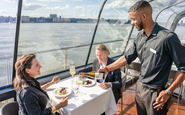Server pouring wine during lunch on a cruise with river view.