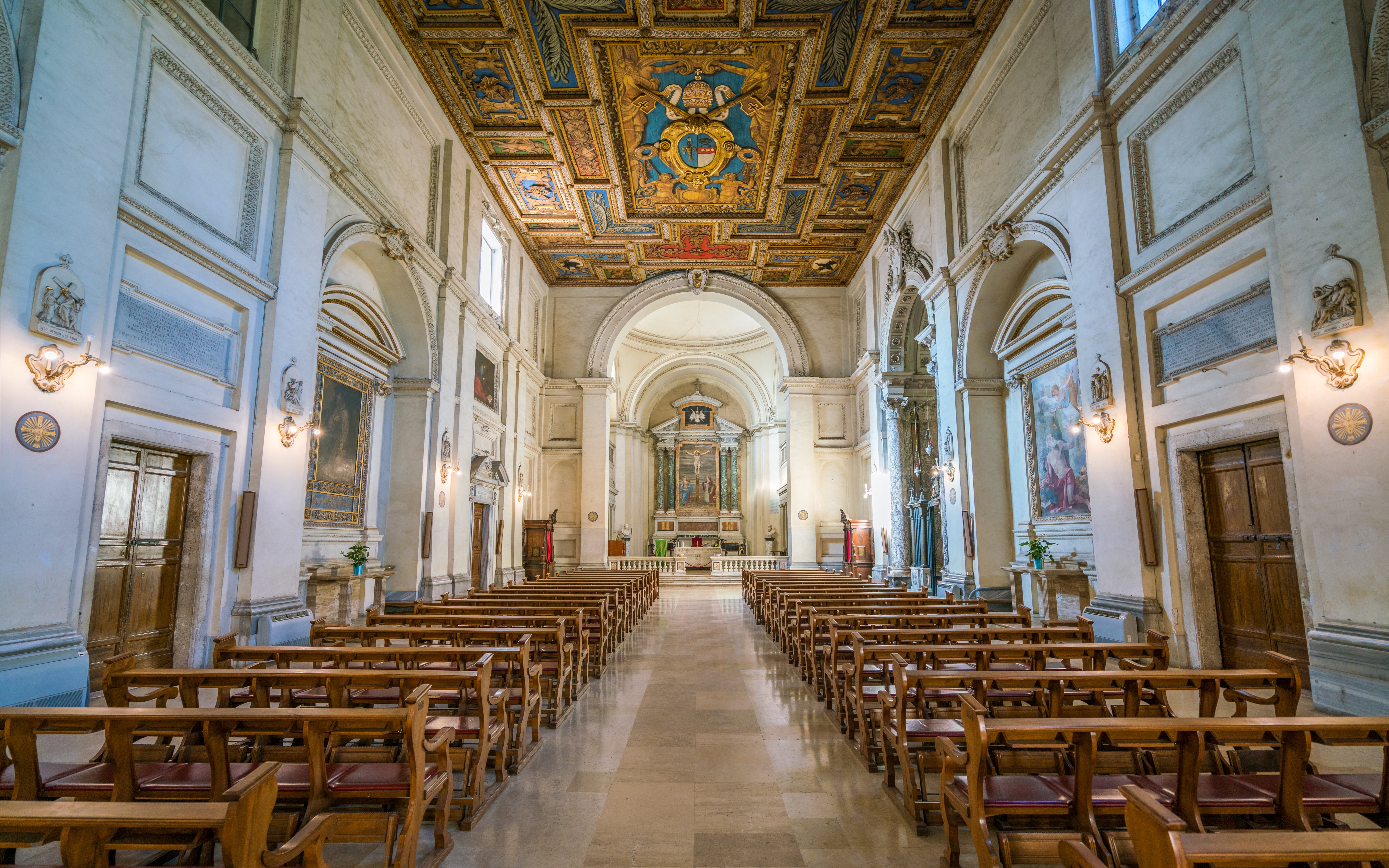 Interior of Basilica of San Sebastiano in Rome with ornate ceiling and wooden pews.