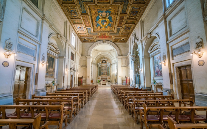Interior of Basilica of San Sebastiano in Rome with ornate ceiling and wooden pews.
