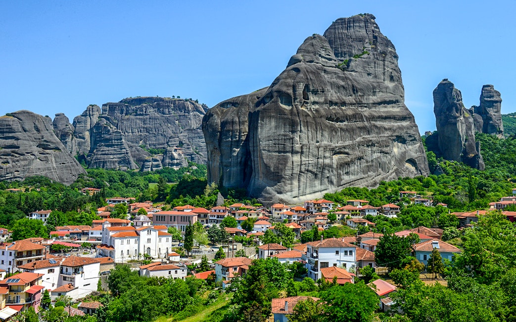 Meteora rock formations with monasteries above a village in Greece.