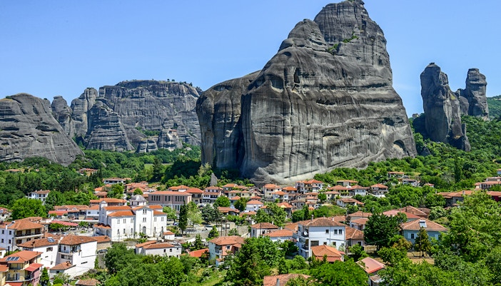 Meteora rock formations with monasteries above a village in Greece.