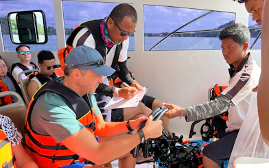 Guides assisting passengers with snorkeling gear on a boat in Phuket.