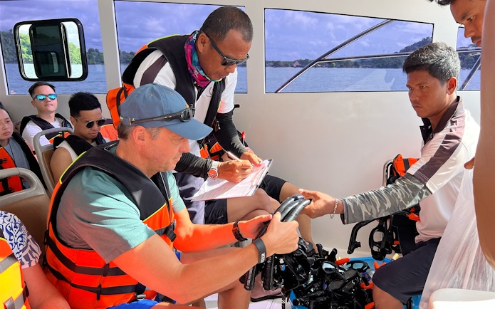 Guides assisting passengers with snorkeling gear on a boat in Phuket.