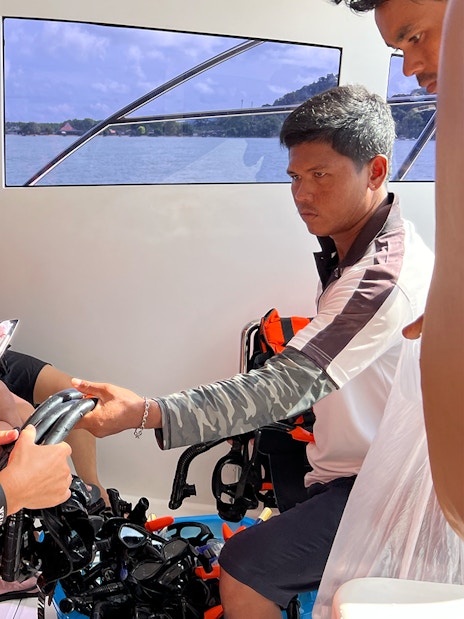Guides assisting passengers with snorkeling gear on a boat in Phuket.