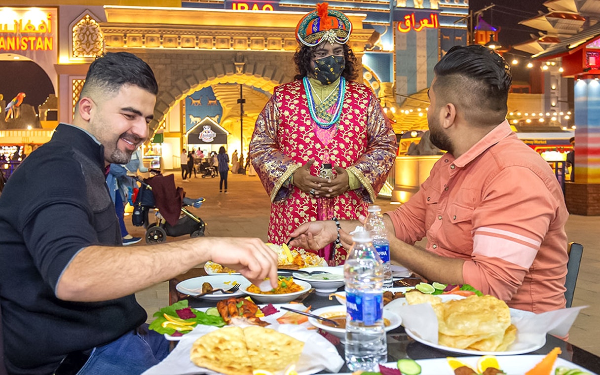 Dining at Global Village Dubai with traditional attire and diverse cuisine.