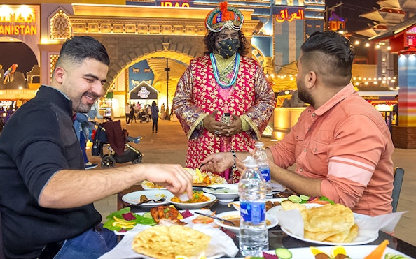 Dining at Global Village Dubai with traditional attire and diverse cuisine.