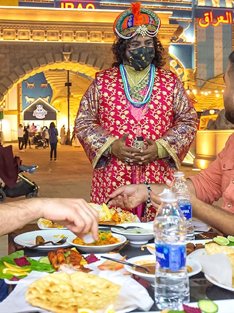 Dining at Global Village Dubai with traditional attire and diverse cuisine.