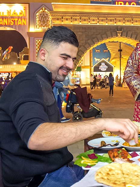 Dining at Global Village Dubai with traditional attire and diverse cuisine.
