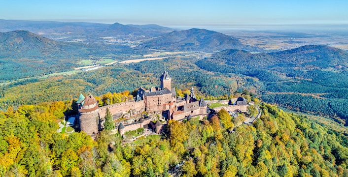 Aerial view of Haut Koenigsbourg Castle surrounded by forested hills in Alsace, France.