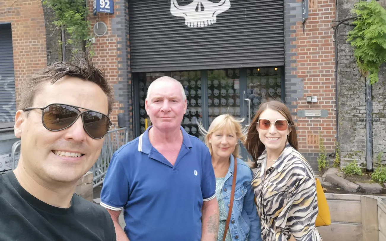 Group of people in front of a brick building with skull artwork in Bermondsey, London.