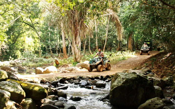 ATV riders on Bel Ombre walking trail through lush forest.
