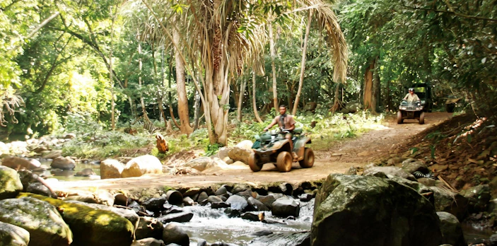 ATV riders on Bel Ombre walking trail through lush forest.