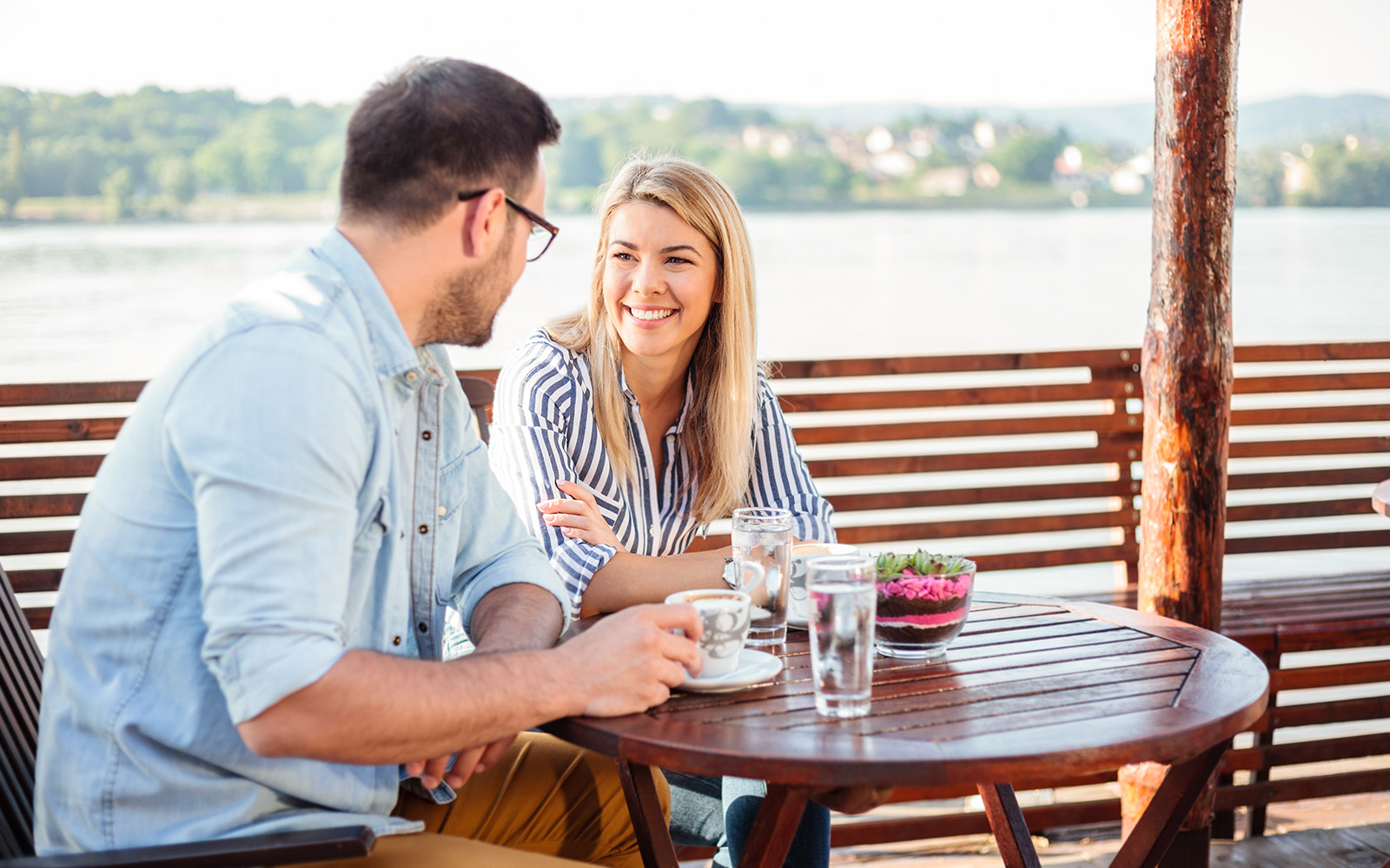 A couple talking and waitng for their meal at a restaurant by the Danube river during the day.