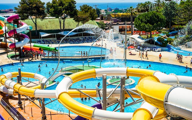 Water slides and pools at Illa Fantasia Water Park, Barcelona, with visitors enjoying the attractions.