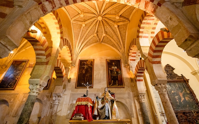 Córdoba Cathedral-Mosque interior with arches and religious statue.