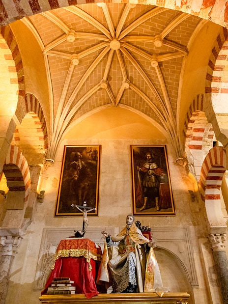Córdoba Cathedral-Mosque interior with arches and religious statue.