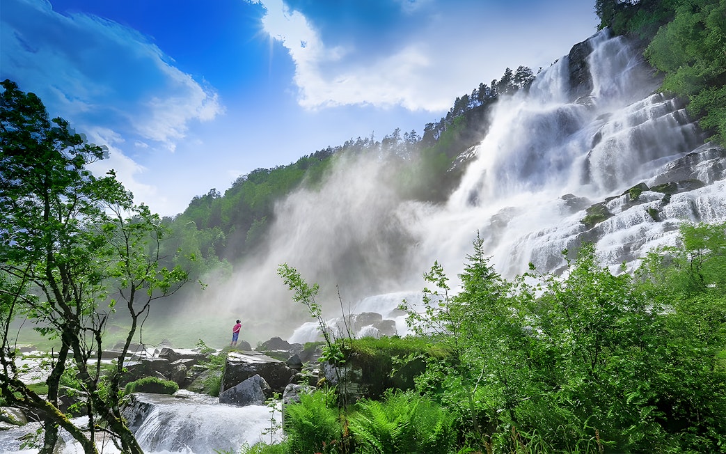 Waterfall in lush green landscape near Bergen, part of the Nærøyfjord cruise and Flåm Railway tour.