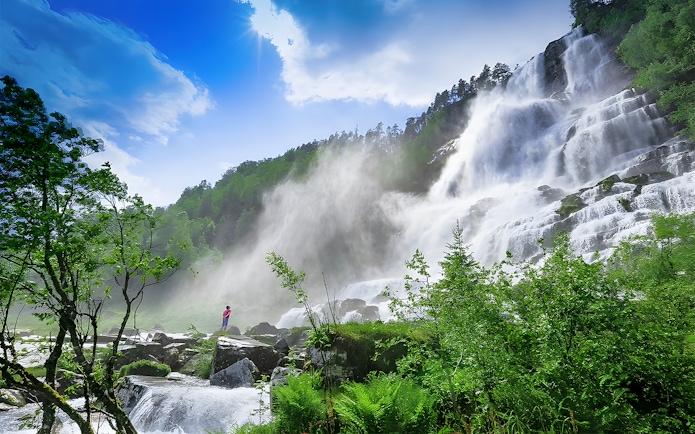 Waterfall in lush green landscape near Bergen, part of the Nærøyfjord cruise and Flåm Railway tour.