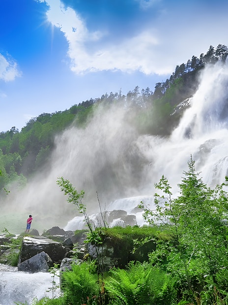 Waterfall in lush green landscape near Bergen, part of the Nærøyfjord cruise and Flåm Railway tour.