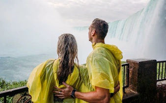Couple in yellow ponchos viewing Niagara Falls, Canada from a lookout point.