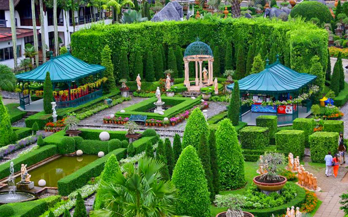 Nong Nooch Tropical Garden with manicured hedges, statues, and gazebos in Pattaya, Thailand.