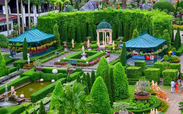 Nong Nooch Tropical Garden with manicured hedges, statues, and gazebos in Pattaya, Thailand.