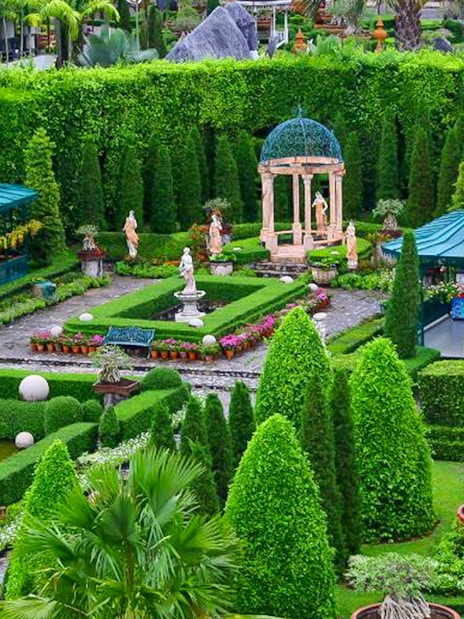 Nong Nooch Tropical Garden with manicured hedges, statues, and gazebos in Pattaya, Thailand.