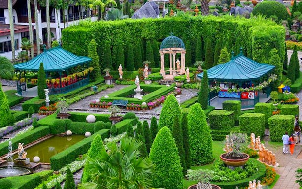 Nong Nooch Tropical Garden with manicured hedges, statues, and gazebos in Pattaya, Thailand.