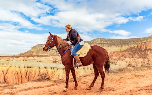 Horseback rider exploring Cappadocia's valleys with unique rock formations.