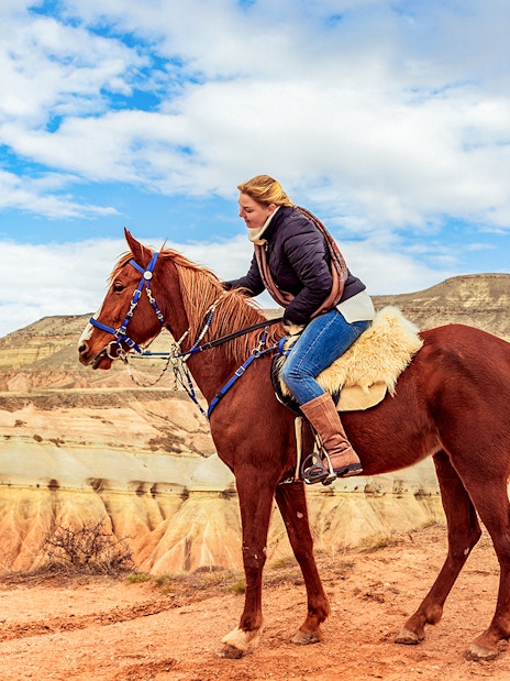 Horseback rider exploring Cappadocia's valleys with unique rock formations.
