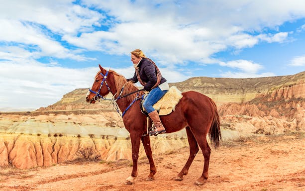 Horseback rider exploring Cappadocia's valleys with unique rock formations.