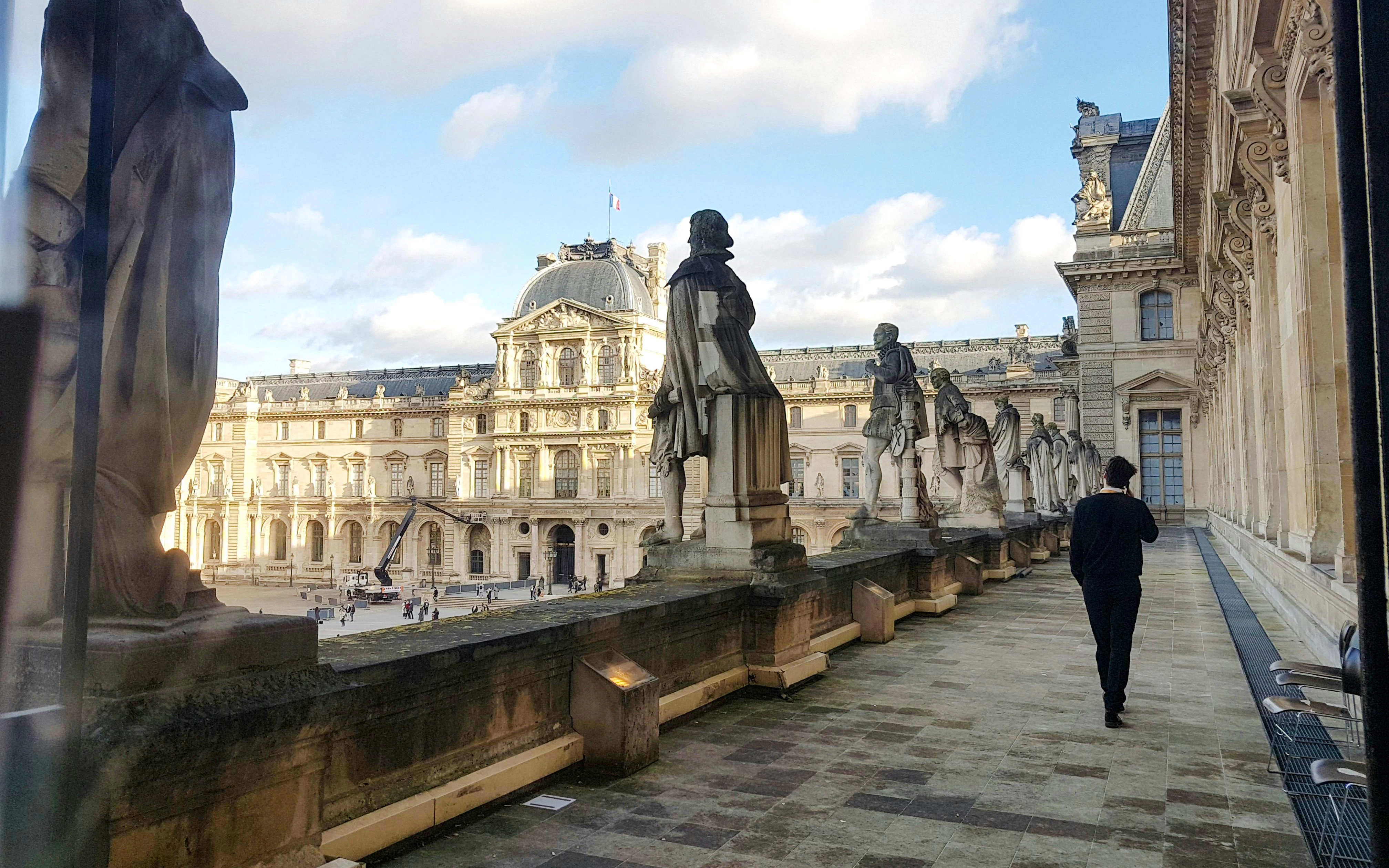 Statues overlooking Cour Napoléon at the Louvre Museum, Paris.