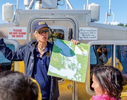 Guide with map addressing group on Vancouver whale watching tour boat.
