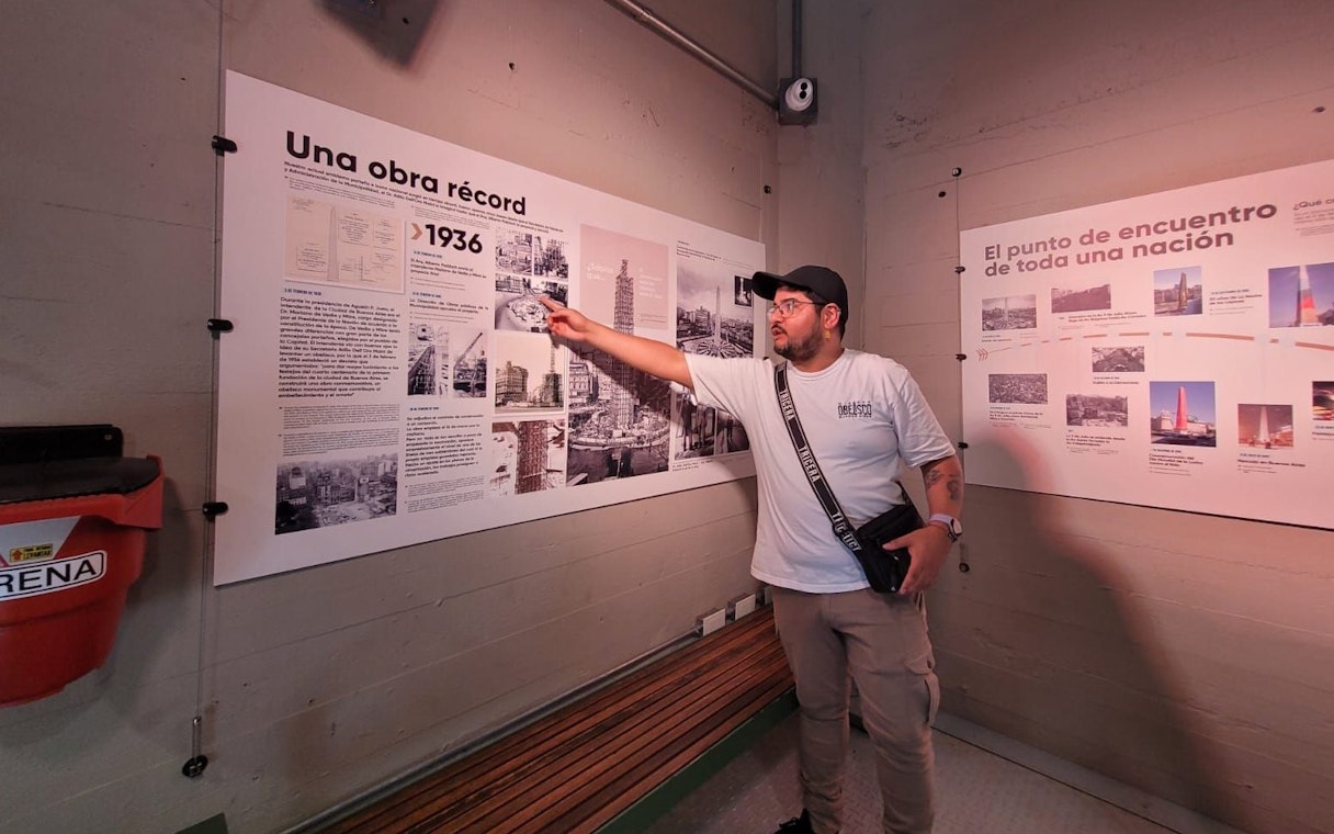 Tourist with guide explaining history at Obelisco de Buenos Aires, Argentina.