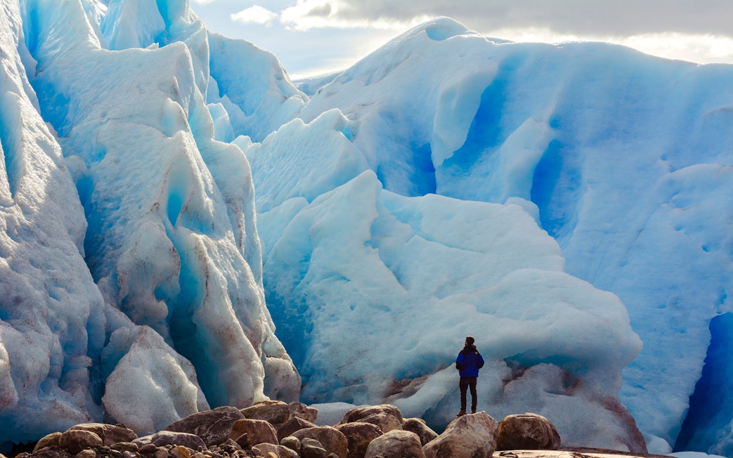Person in front of large blue glacier on Copia de Safari Azul tour.
