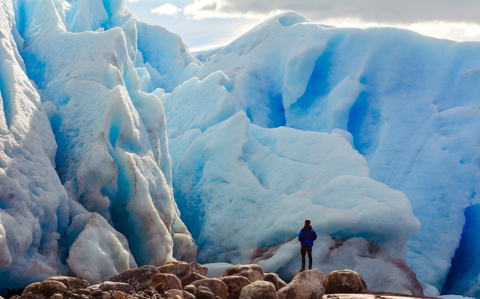 Person in front of large blue glacier on Copia de Safari Azul tour.