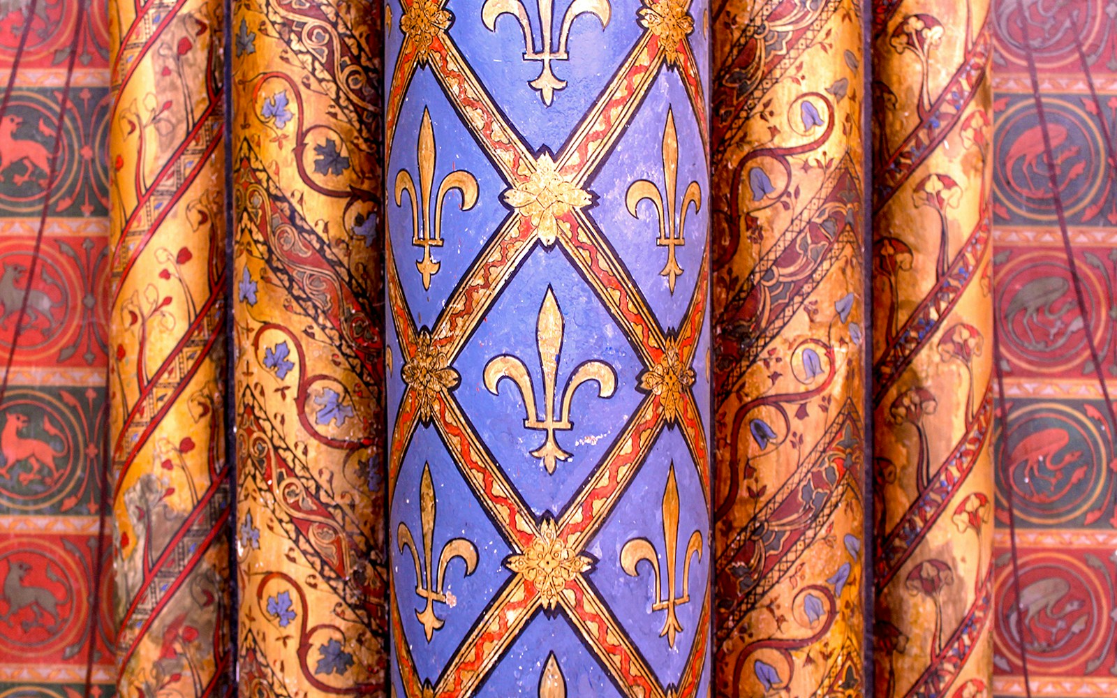 Slender red columns with gold and green patterns in lower chapel ceiling, Sainte-Chapelle, Paris.